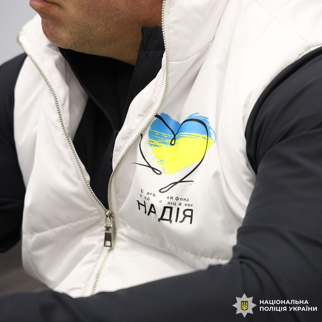 Чоловік в білому жилеті з принтом у вигляді серця, заповненого кольорами українського прапора.
