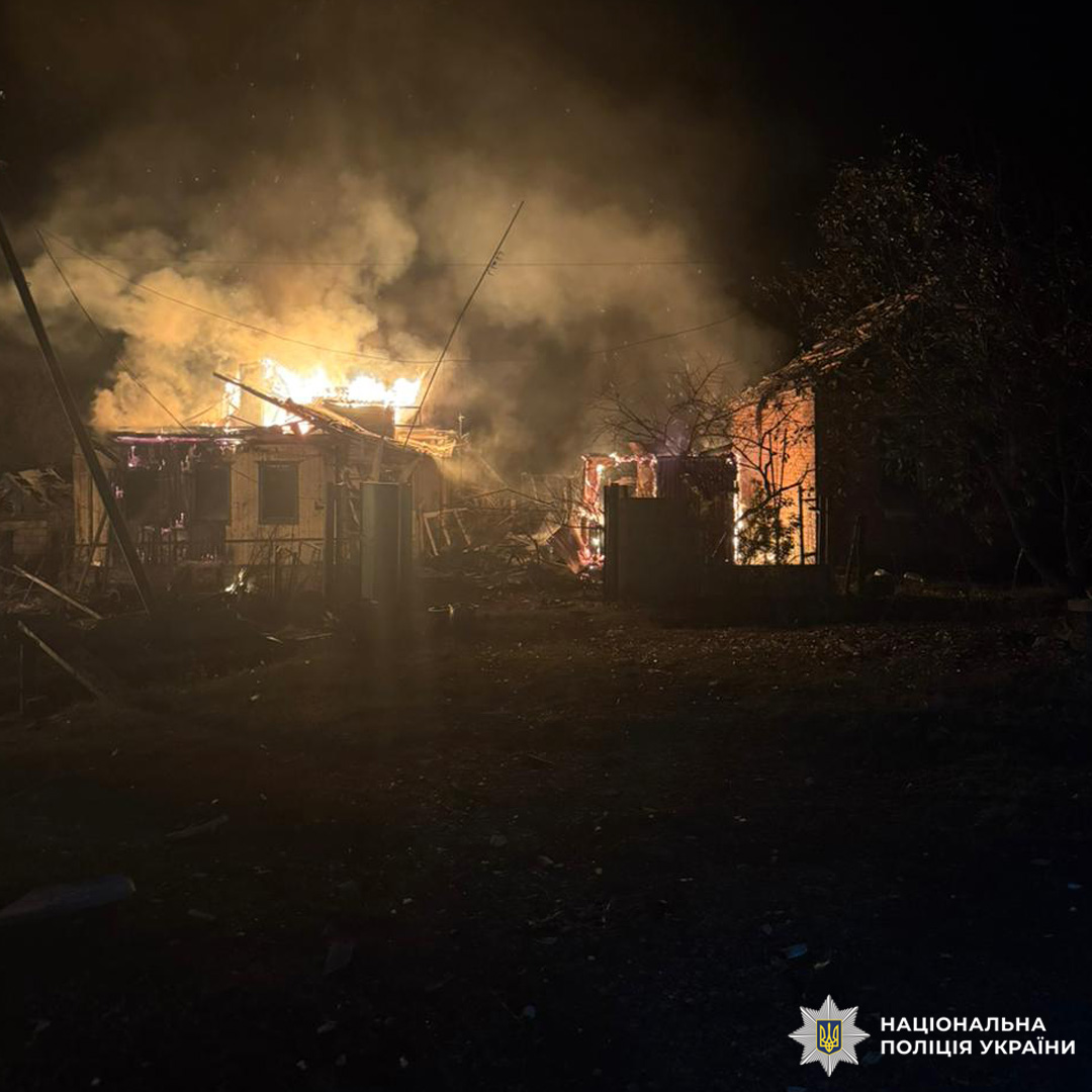 Нічна сцена в житловому районі: будівля охоплена сильним полум’ям, густий дим підіймається в небо. Яскраво-оранжеві язики вогню вириваються з даху та вікон.