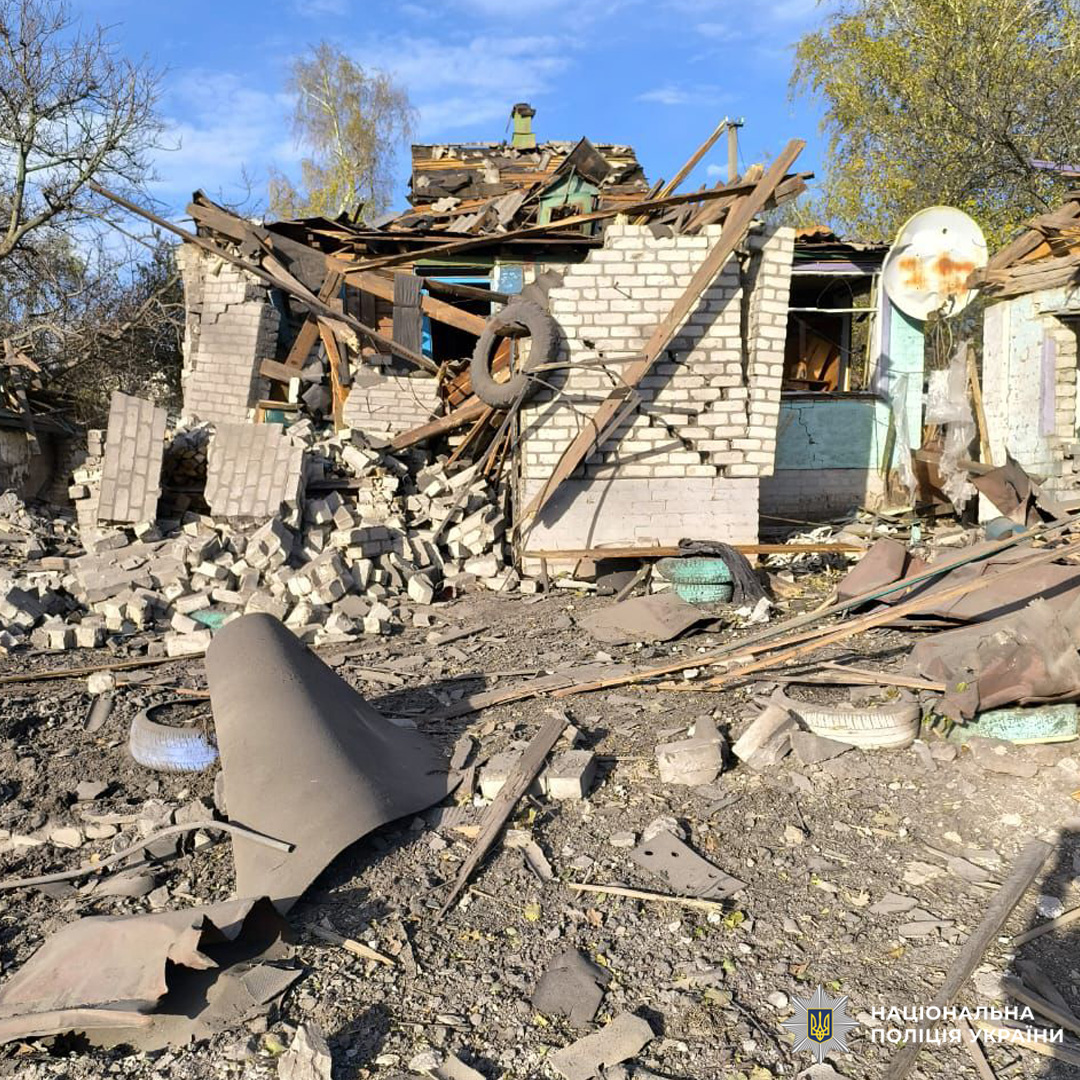 Зруйнована цегляна будівля після вибуху: частково обвалена конструкція, уламки, знищений дах, супутникова антена, побутові речі серед руїн.