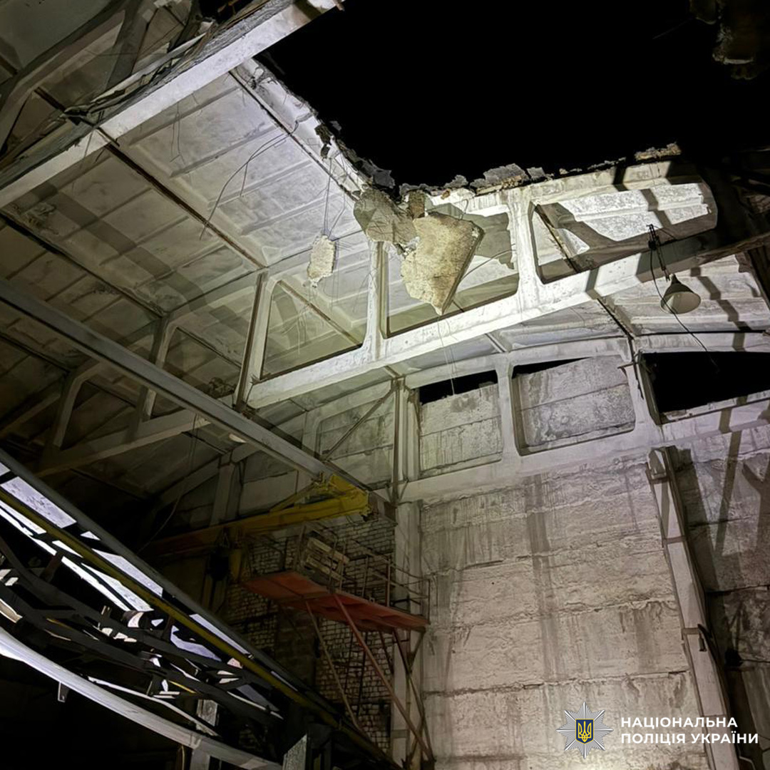 Пошкоджене приміщення промислового типу: пробитий дах, уламки, металеві балки, ознаки вибуху або удару.