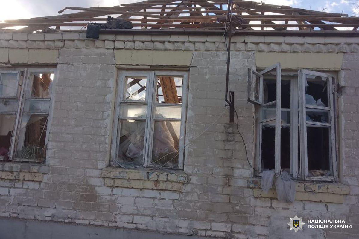 На фото цегляна споруда з частково зруйнованим дахом, пошкодженими вікнами та видимими уламками всередині. Дерев’яні балки та відсутність частини покрівлі свідчать про серйозні конструктивні ушкодження.