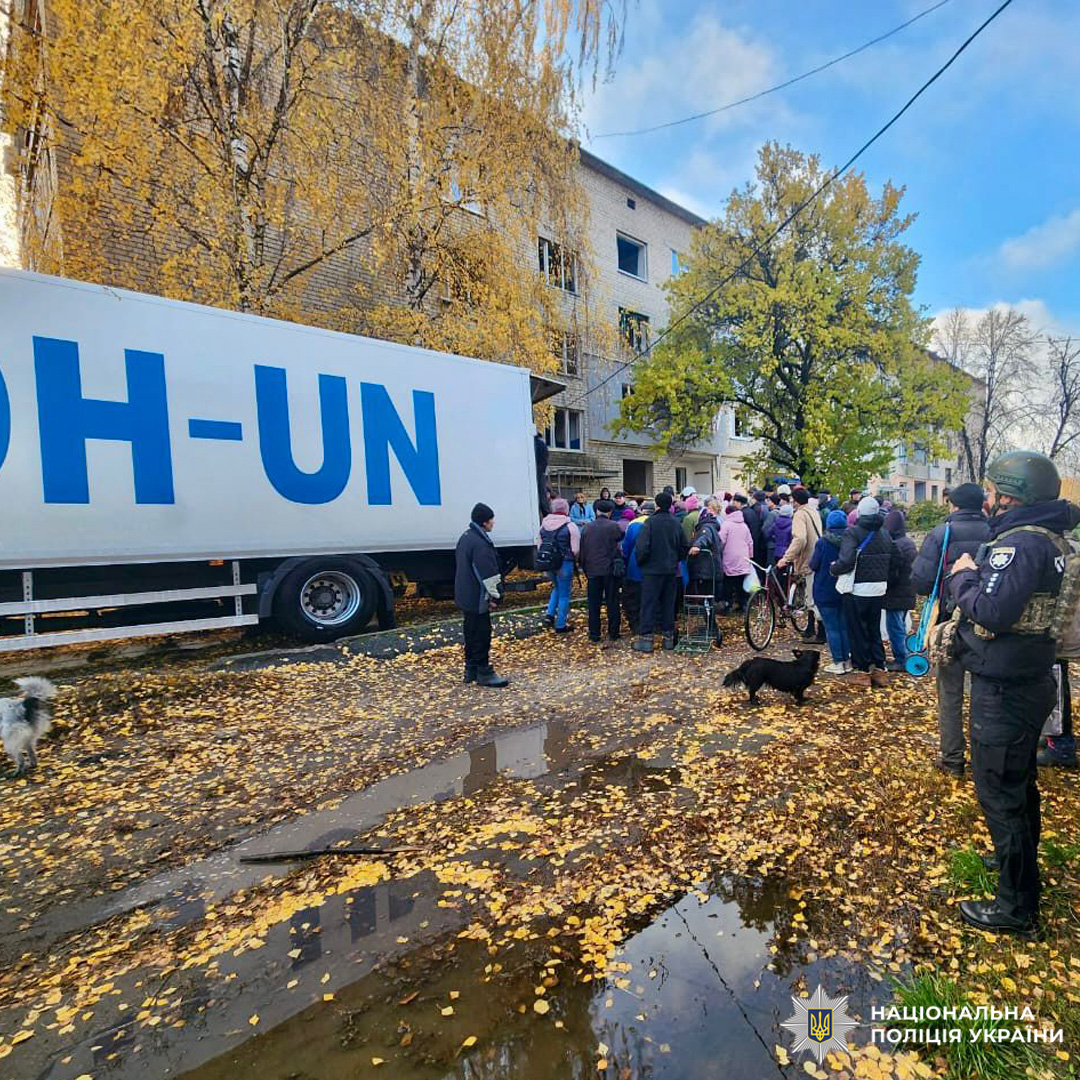 Люди біля вантажівки у житловому районі; осінь. Присутні службовці, мешканці.