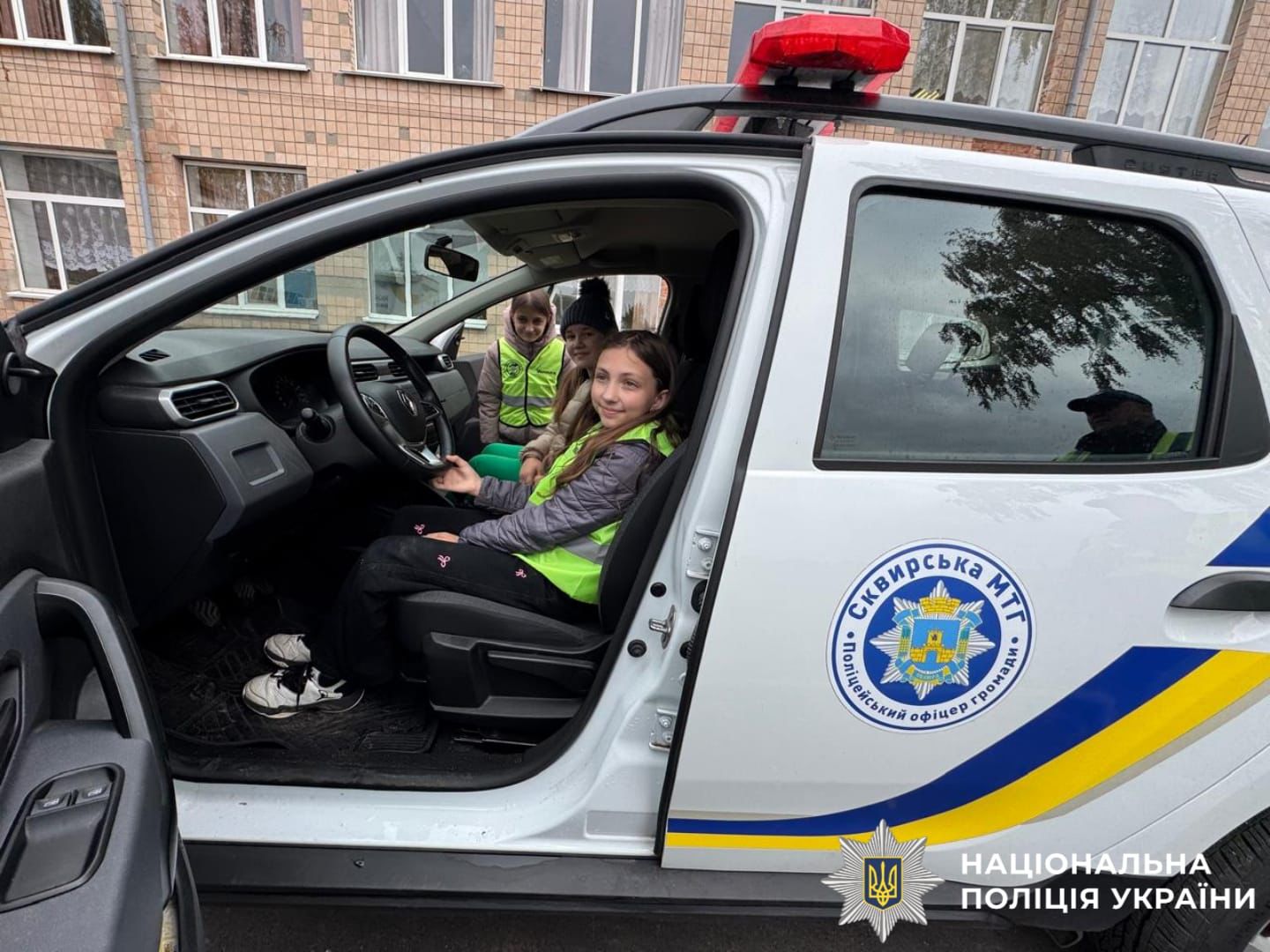 На фото діти у поліцейському автомобілі.