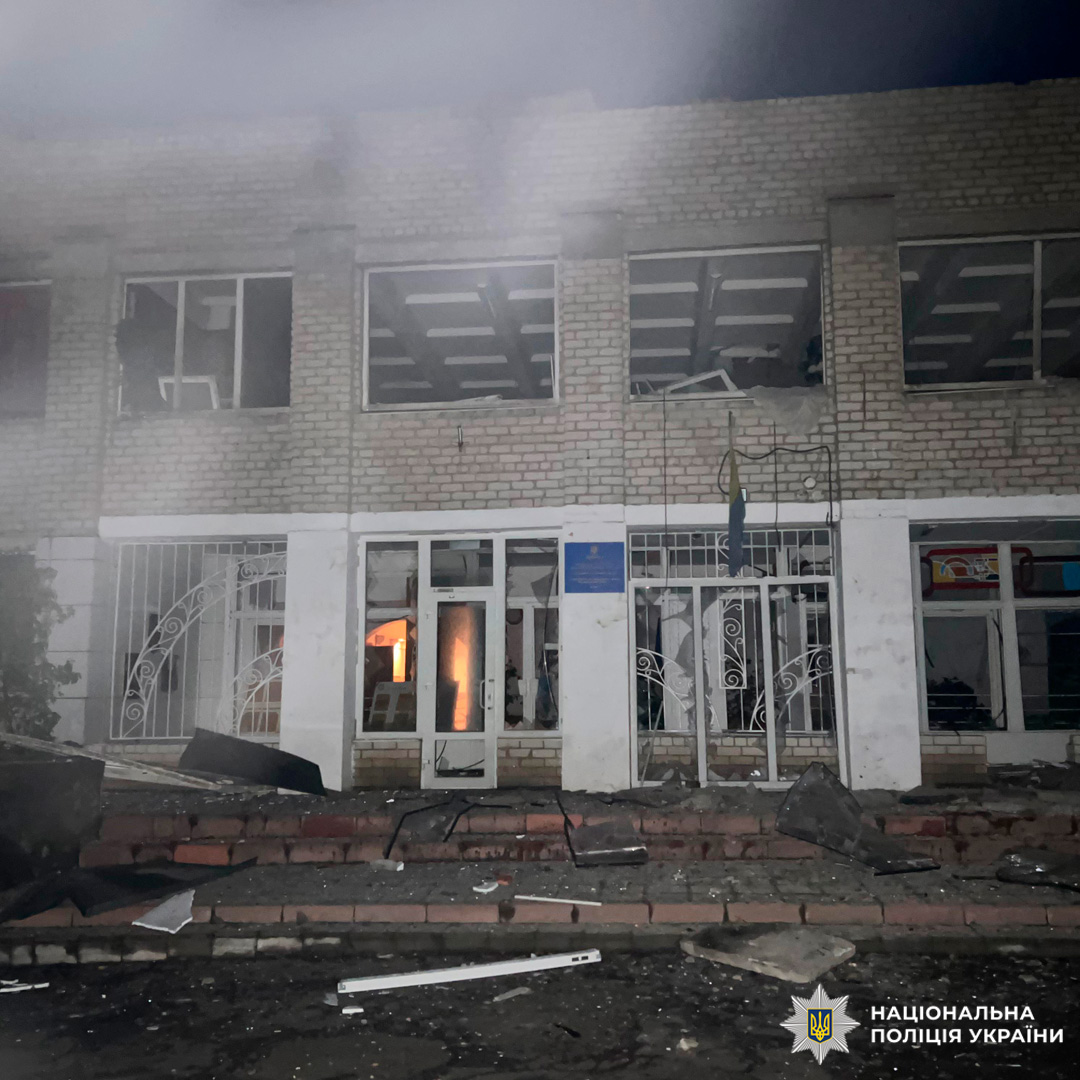 Пошкоджена двоповерхова будівля після вибуху: вибиті вікна, уламки біля входу, вогонь всередині.