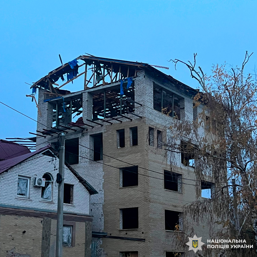 Багатоповерхова будівля зруйнована на верхніх рівнях: обвалені стіни, відкриті балки, висячі уламки.