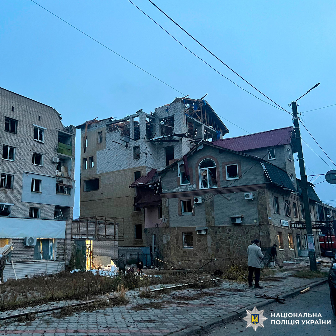 Зруйнована багатоповерхівка в місті: обвалені верхні поверхи, уламки на землі, територія огороджена.