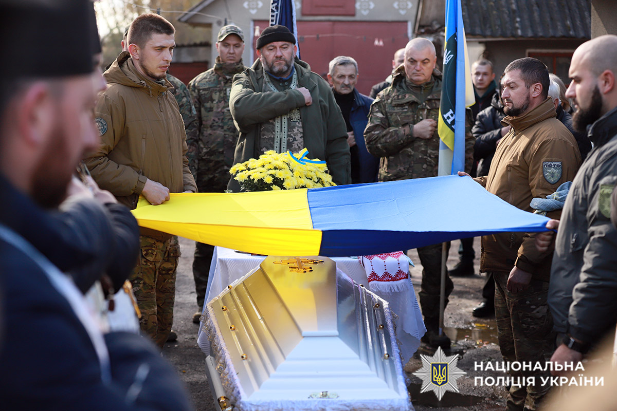 Колеги загиблого поліцейського тримають прапор над його тілом