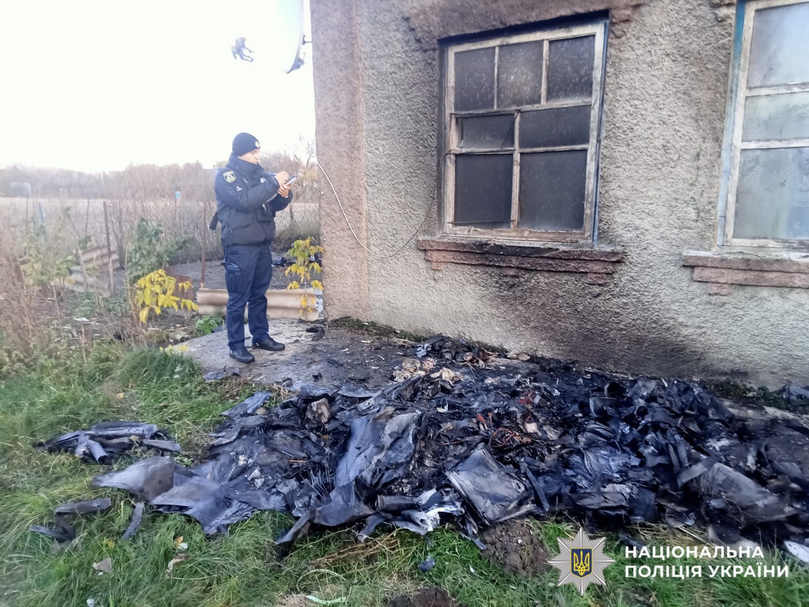 На фотографії зображено поліцейського та наслідки ворожої атаки по території Київської області.