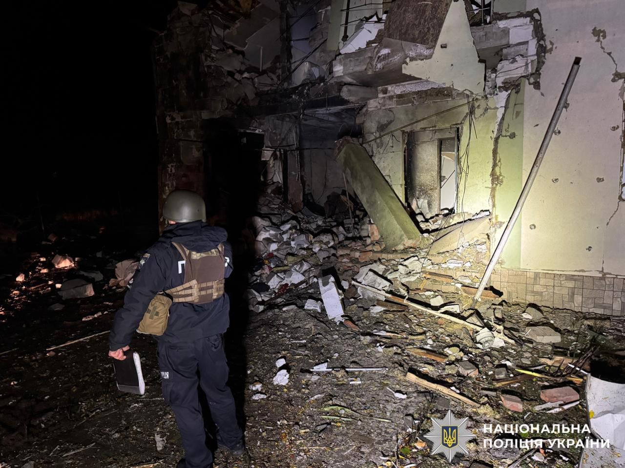 На фотографії зображено поліцейського та наслідки ворожої атаки по території Київської області.