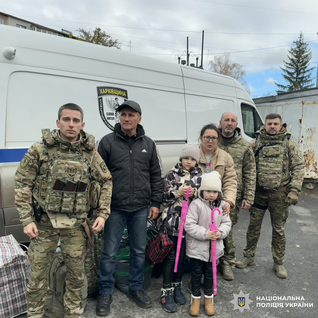 Співробітники Національної поліції України на Харківщині поруч із евакуйованими цивільними чоловіком, жінкою та двома дітьми.