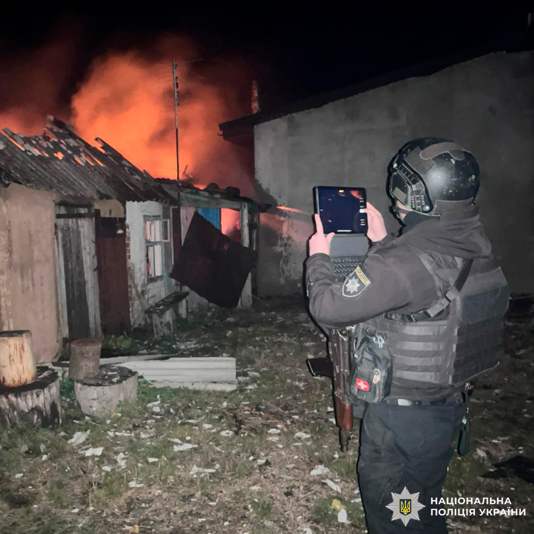 Поліцейський документує нічну пожежу. Вогонь охопив будівлю, дах частково зруйнований.