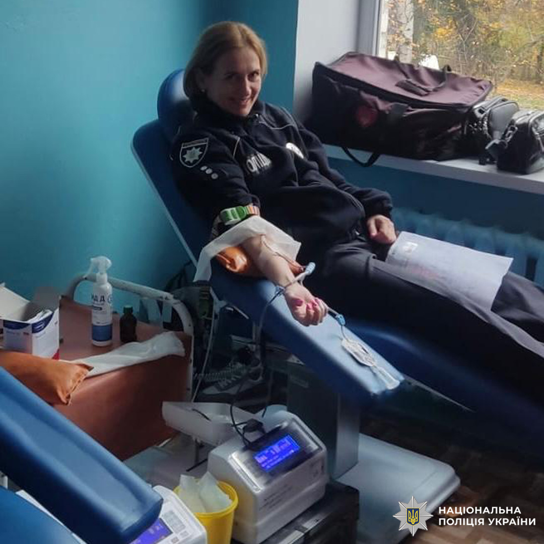 Співробітник поліції здає кров у медичному закладі. Донор перебуває у спеціальному кріслі, до його руки під’єднано систему для забору крові. Поруч медичне обладнання та антисептичні засоби.