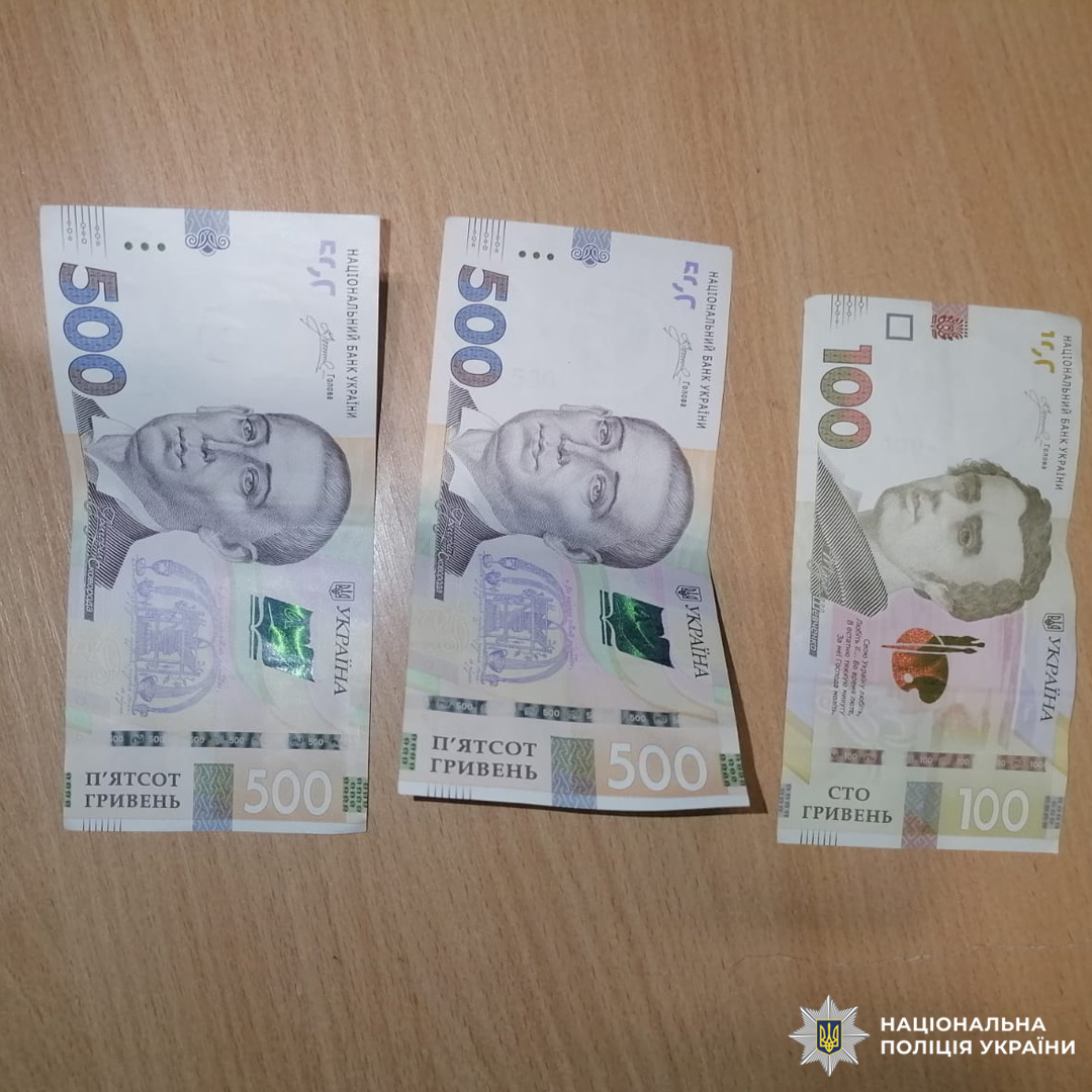 Три банкноти на дерев’яній поверхні: дві по 500 гривень і одна 100 гривень.