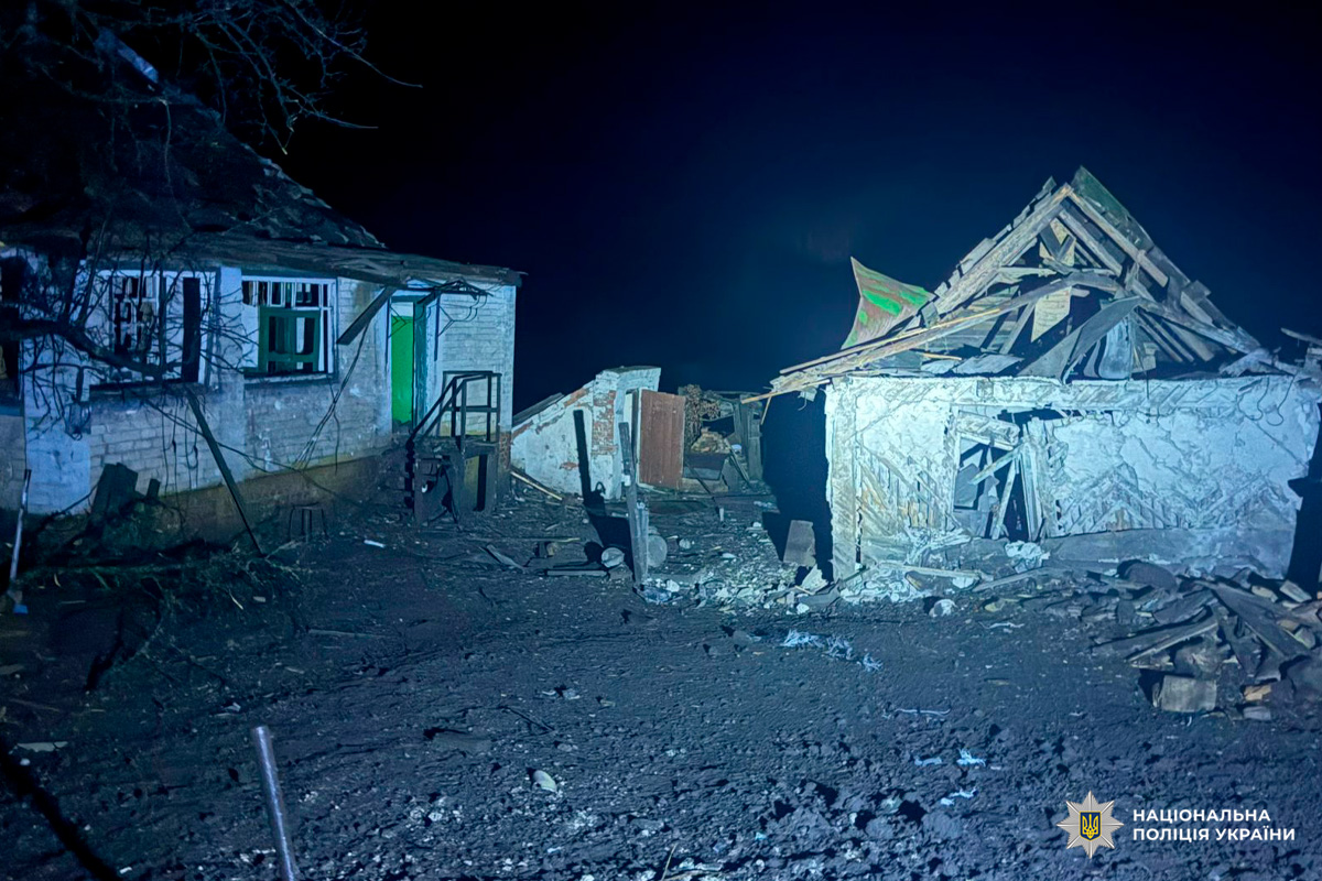 На фото два житлові будинки, один із яких зазнав значних пошкоджень: частково обвалений дах, навколо уламки будівельних конструкцій. Другий будинок виглядає менш пошкодженим.