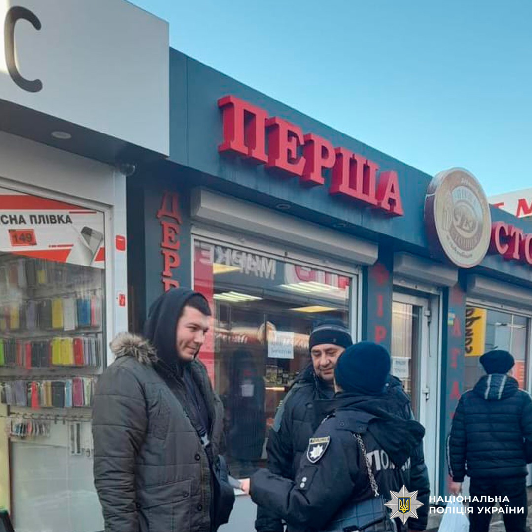 Поліцейський спілкується з чоловіком біля магазину.