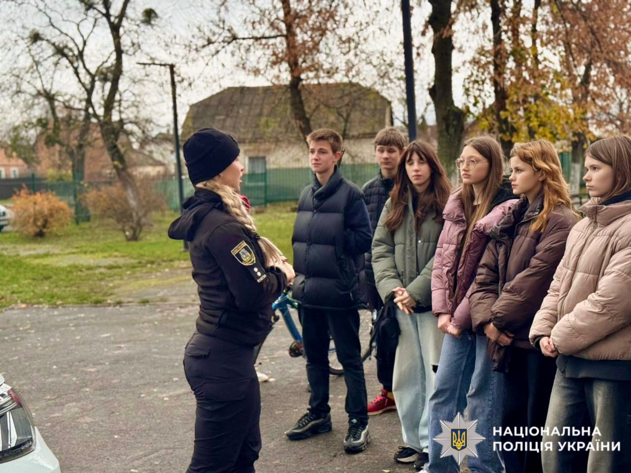 На фотографії зображено дітей та працівника поліції, яка проводить для них пізнавальний захід.