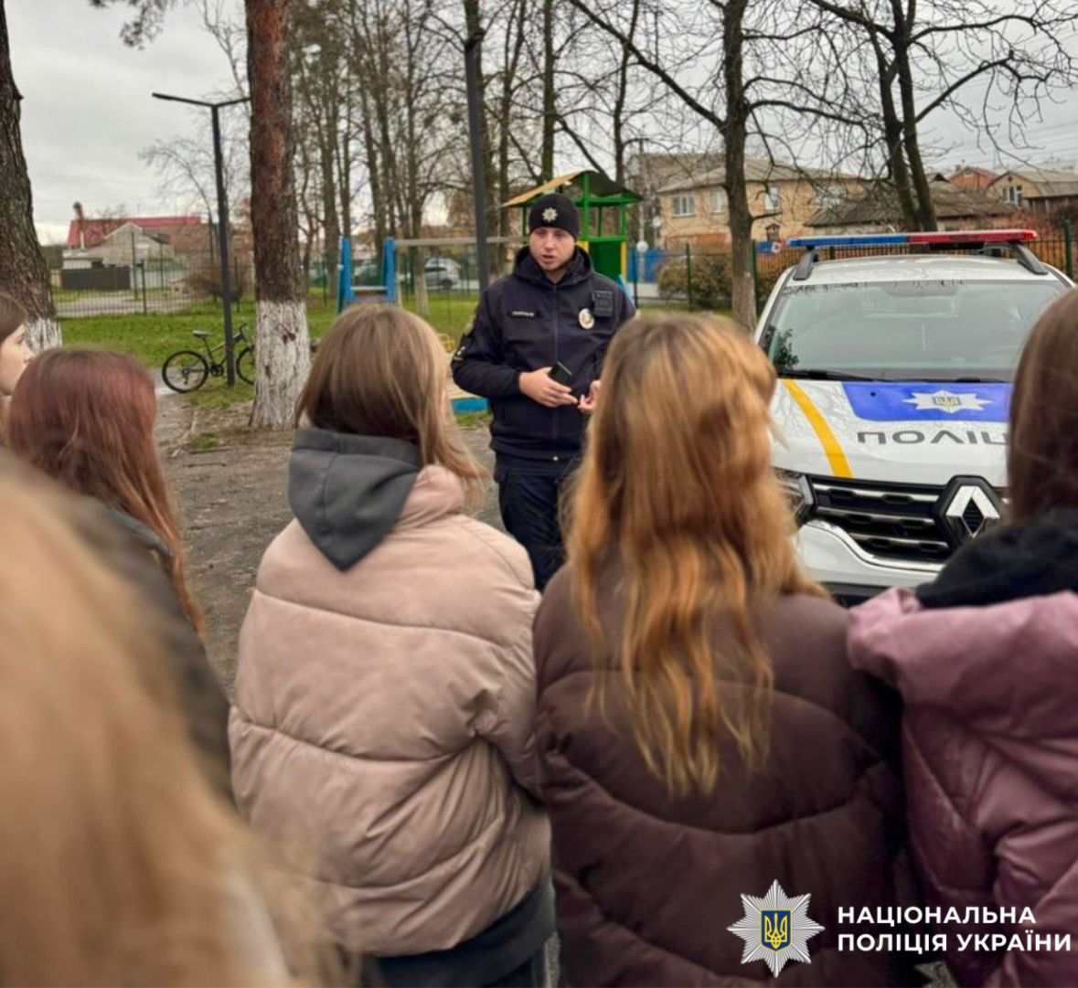На фотографії зображено дітей та працівника поліції, який проводить для них пізнавальний захід.