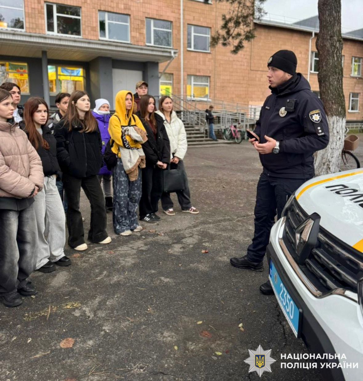 На фотографії зображено дітей та працівника поліції, який проводить для них пізнавальний захід.