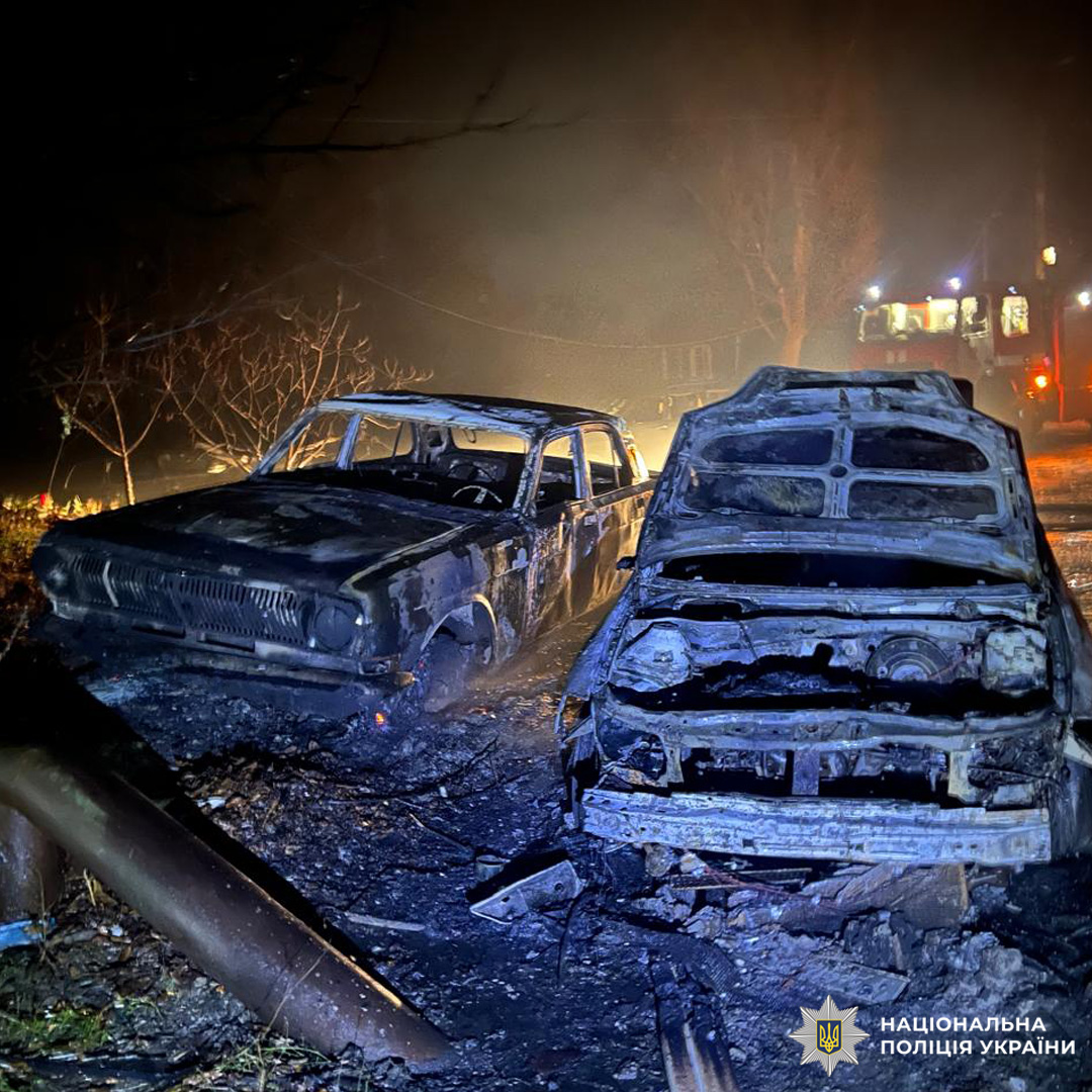 Два повністю вигорілі автомобілі, з обгорілими корпусами та відкритими салонами. Навколо сліди пожежі, уламки.