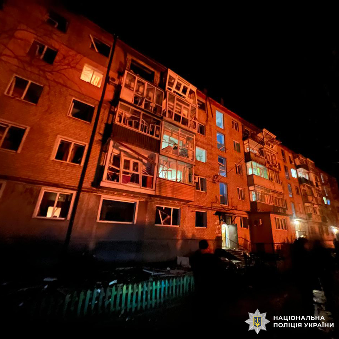 Багатоповерховий житловий будинок уночі, пошкоджені вікна та балкони, що свідчить про наслідки вибуху.