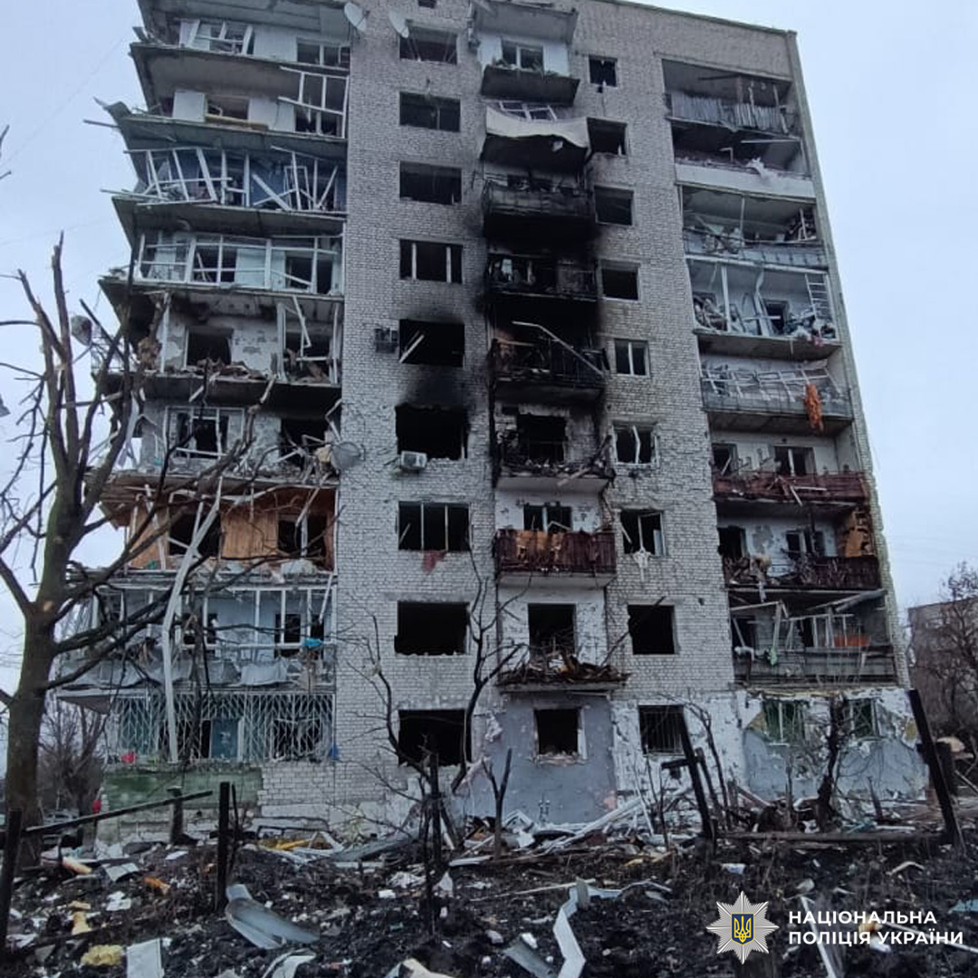 Багатоповерховий житловий будинок із серйозними пошкодженнями фасаду, вікон і балконів, частково зруйнований внаслідок потужного вибуху.