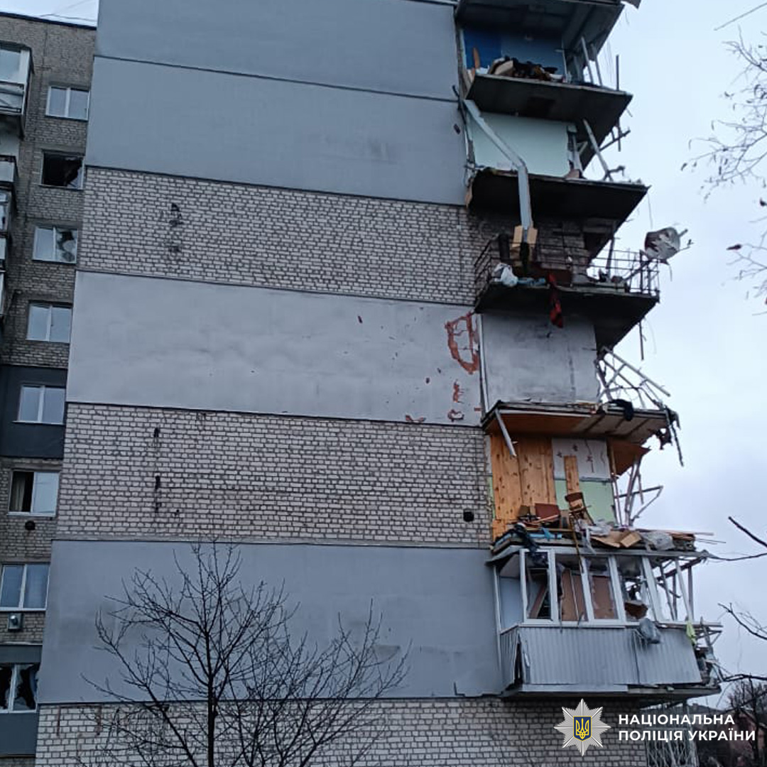 Багатоповерховий житловий будинок із серйозними пошкодженнями фасаду, вікон і балконів, частково зруйнований внаслідок потужного вибуху.