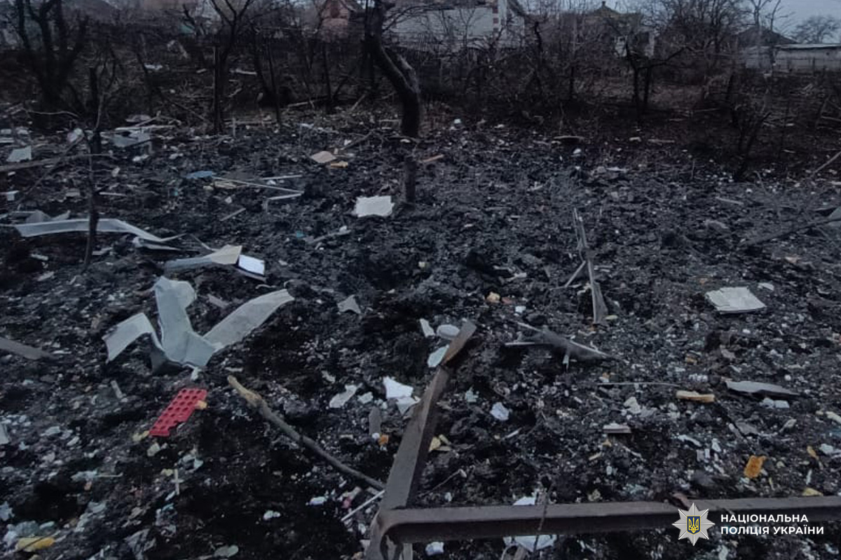 Зруйнована територія з розкиданими уламками, обгорілою землею та залишками металевих конструкцій.