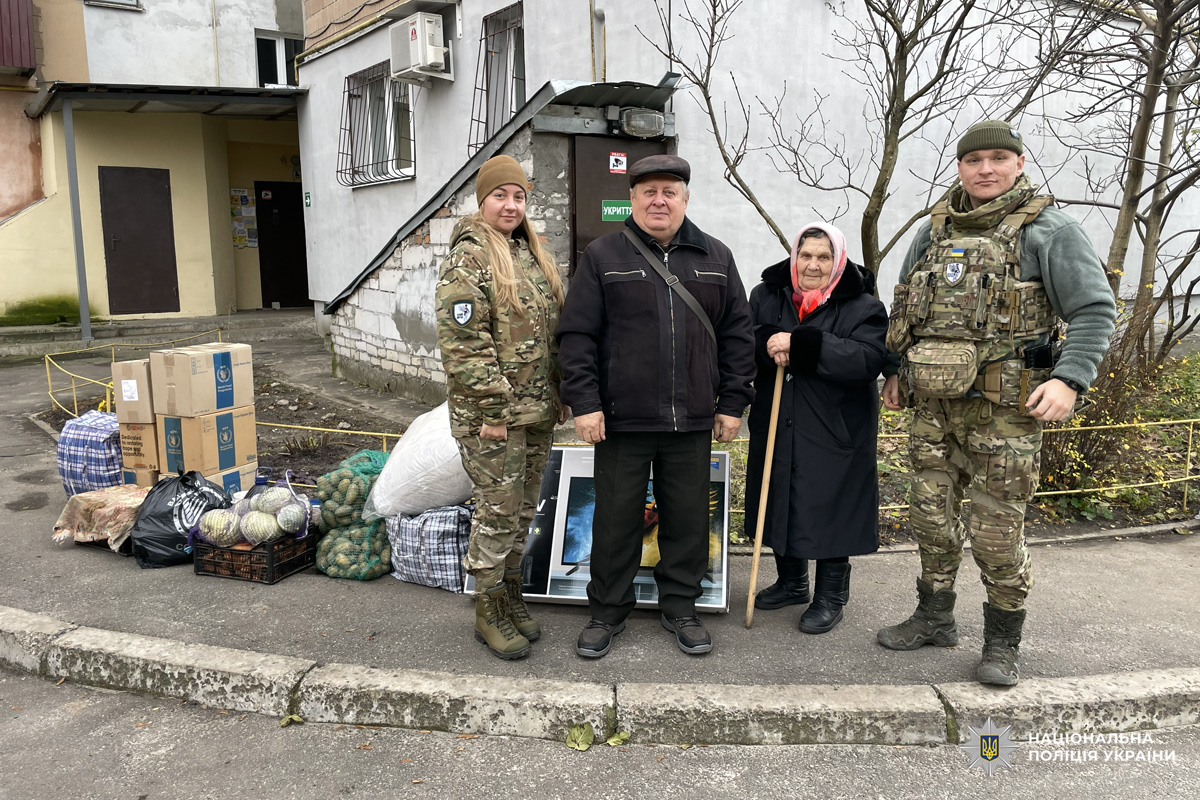 Двоє поліцейських у камуфляжі, цивільні чоловік і літня жінка з палицею.