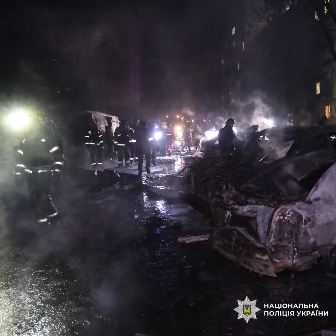 Нічна робота рятувальників та поліції на місці масштабних руйнувань. Задимлення, уламки, знищені автомобілі.