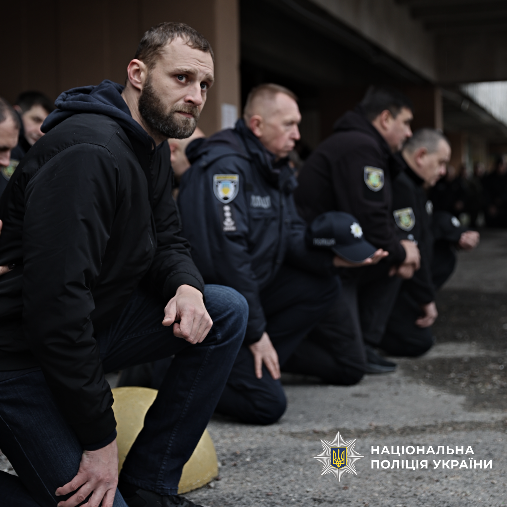 Колона з побратимів які стоять на одному коліні перед загиблим бійцем