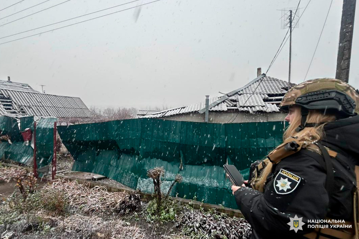 Поліцейський у зимовому спорядженні на тлі пошкоджених будинків. Сніг, огляд місця події.