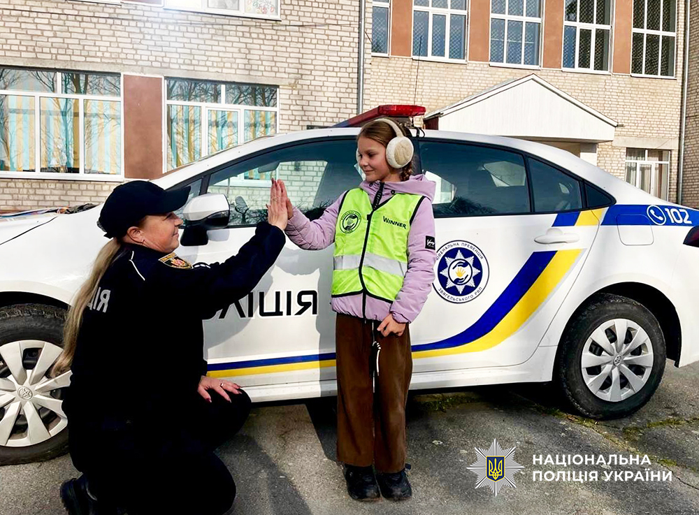 Ювенальна поліцейська з дівчинкою біля службового авто.