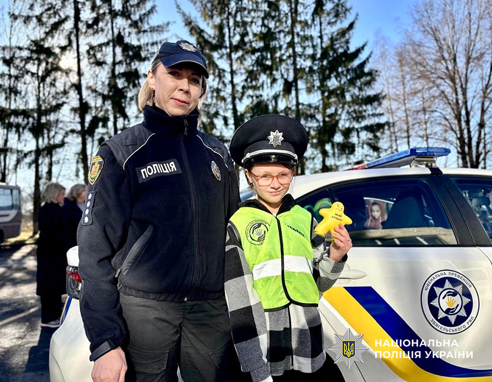 Поліцейська з дівчинкою біля службового авто.