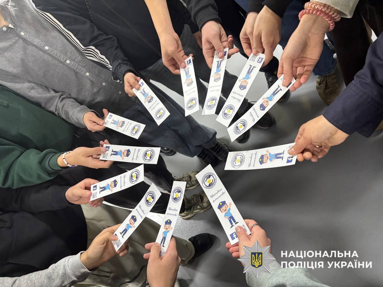 На фото зображені руки дітей, які тримають однакові брошури.