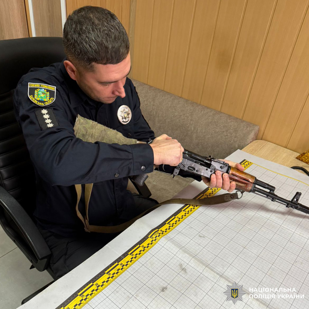 Поліцейський оглядає автомат АК у службовому приміщенні.