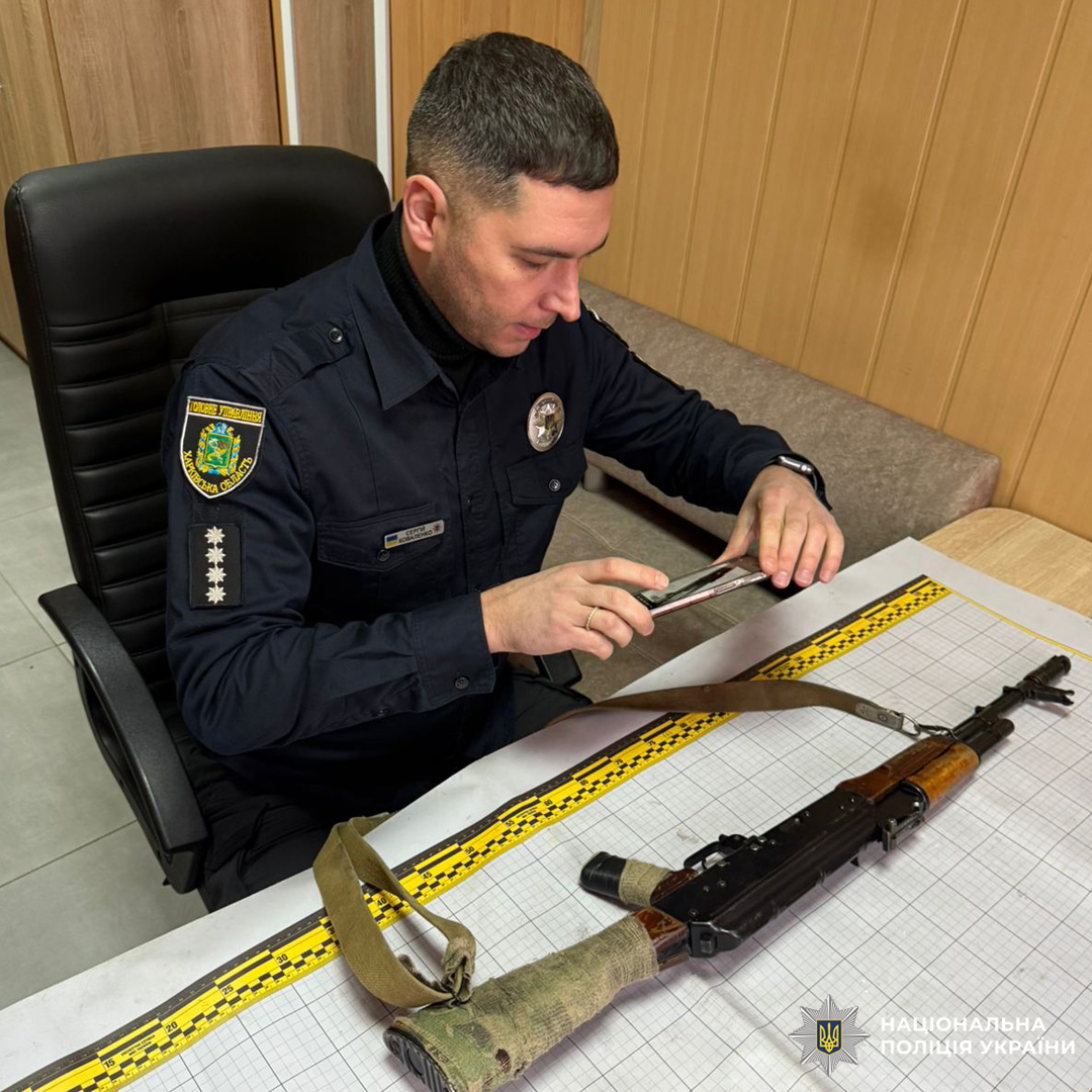 Поліцейський оглядає автомат АК у службовому приміщенні.