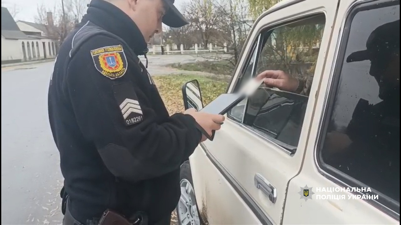 Поліцейський перевіряє водійське посвідчення керманича