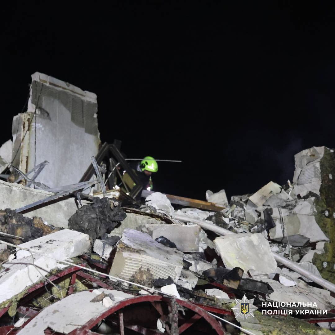 Нічне фото заваленої будівлі: уламки бетону, скручені конструкції.