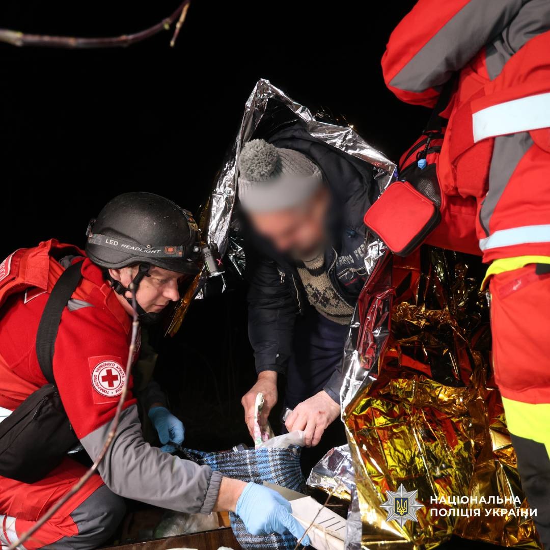 Медики Червоного Хреста надають допомогу постраждалому, загорнутому в термоковдру.