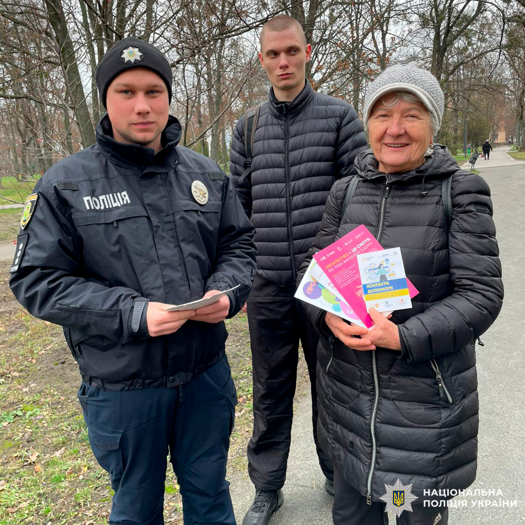 Поліцейський спілкується з літньою жінкою в парку, поширюючи інформаційні матеріали.
