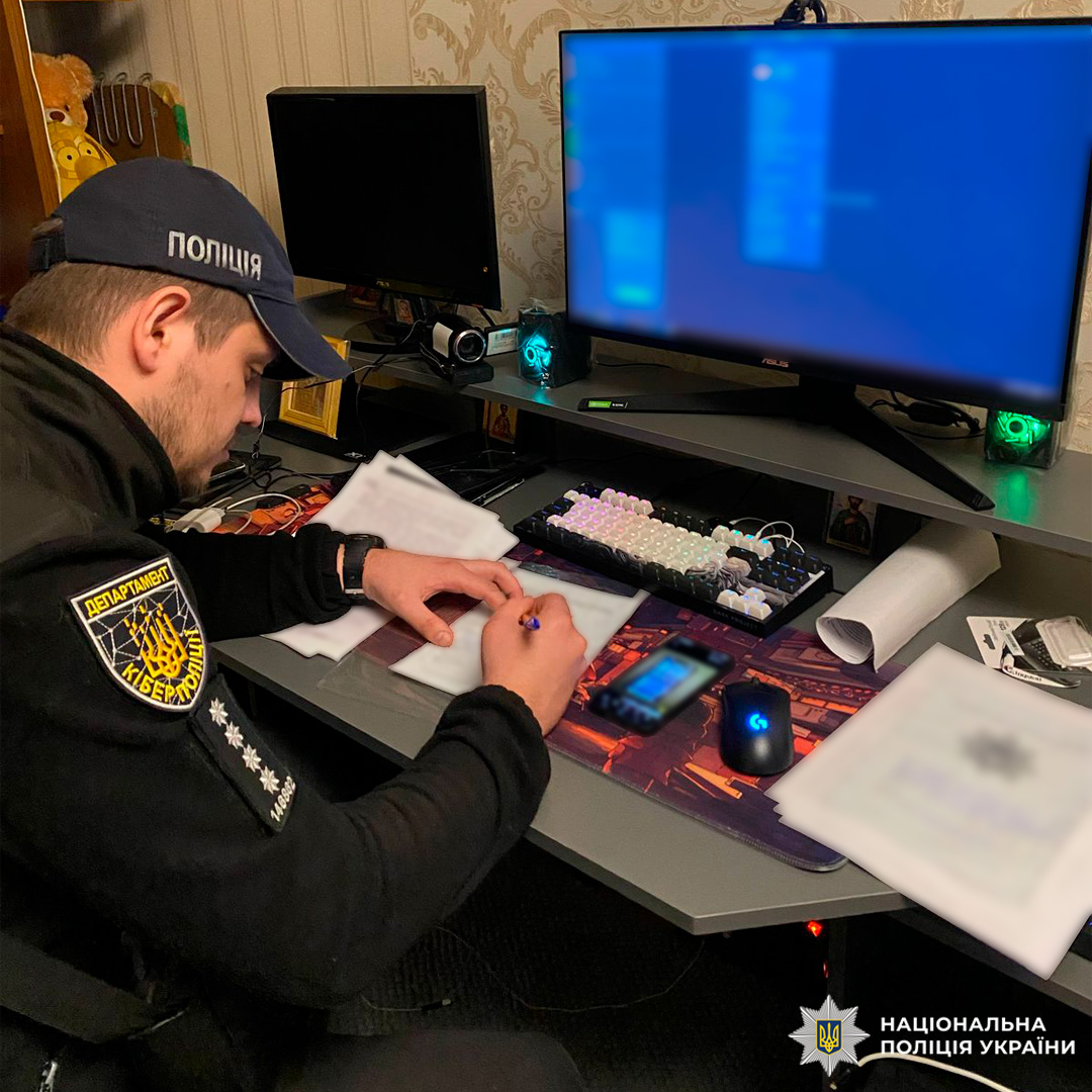 Співробітник кіберполіції України біля комп’ютера, оформлює документи.