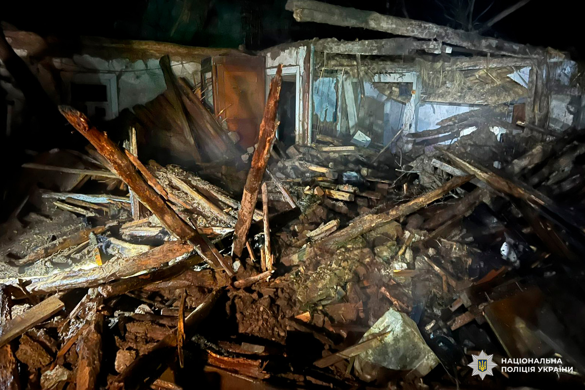 Нічна сцена руйнування: уламки дерев’яних конструкцій і стін після обстрілу чи катастрофи.