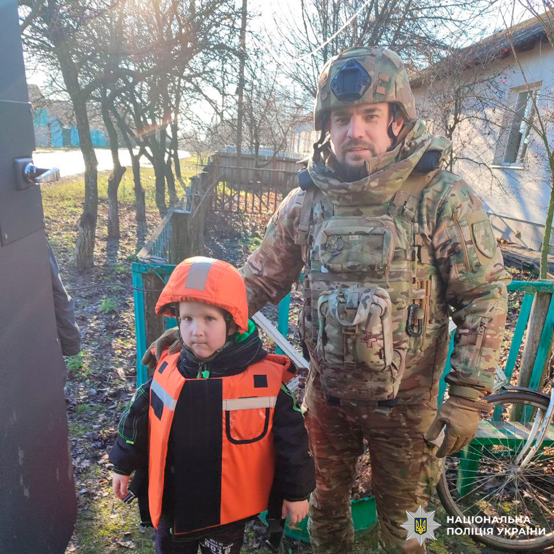 Поліцейський допомагає дитині, момент евакуації.