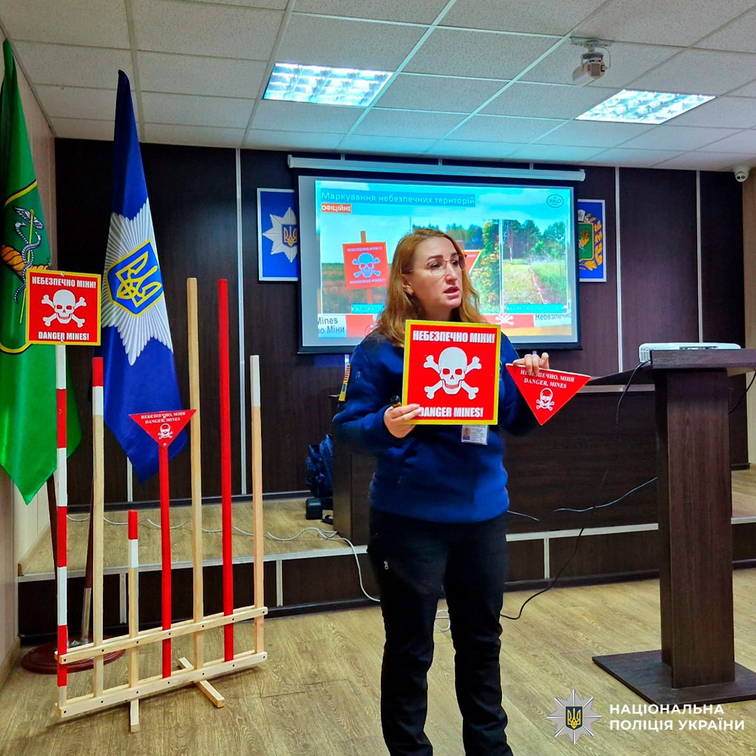 Представник міжнародної благодійної організації з гуманітарного розмінування демонструє попереджувальні знаки про мінну небезпеку під час тренінгу в офіційному приміщенні.