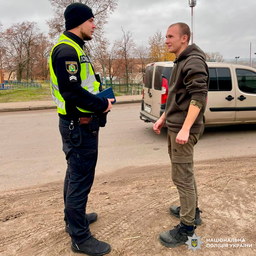 Cпівробітник поліції України у формі та світловідбивальному жилеті спілкується з цивільною особою.