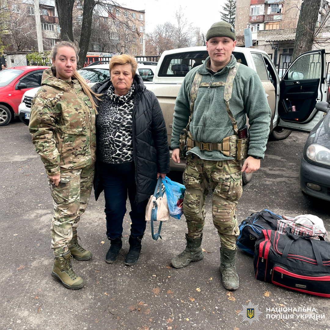 Двоє поліцейських і цивільна особа біля відкритого авто з багажем момент евакуації.