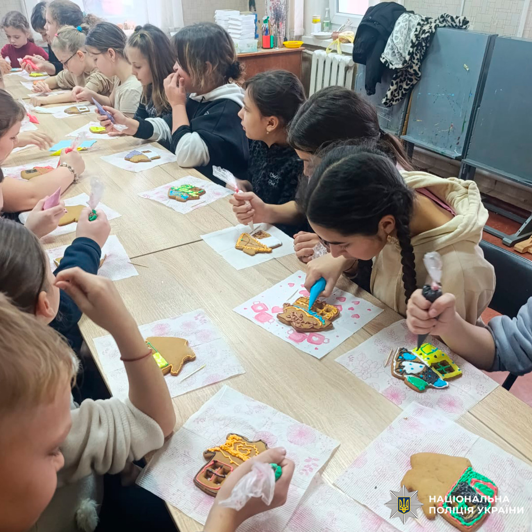 У класному приміщенні група дітей бере участь у майстер-класі з декорування пряників. Кожна дитина працює з кольоровою глазур’ю, створюючи візерунки на фігурних печивах.