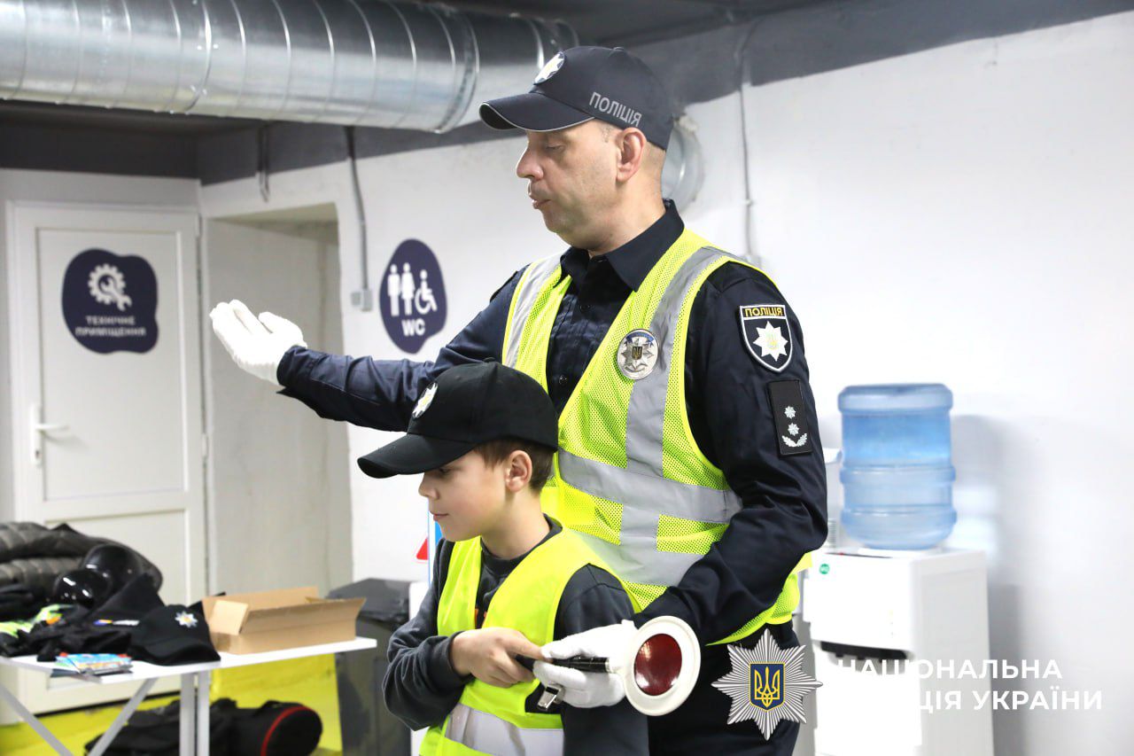 На фото зображено дітину разом з поліцейським.