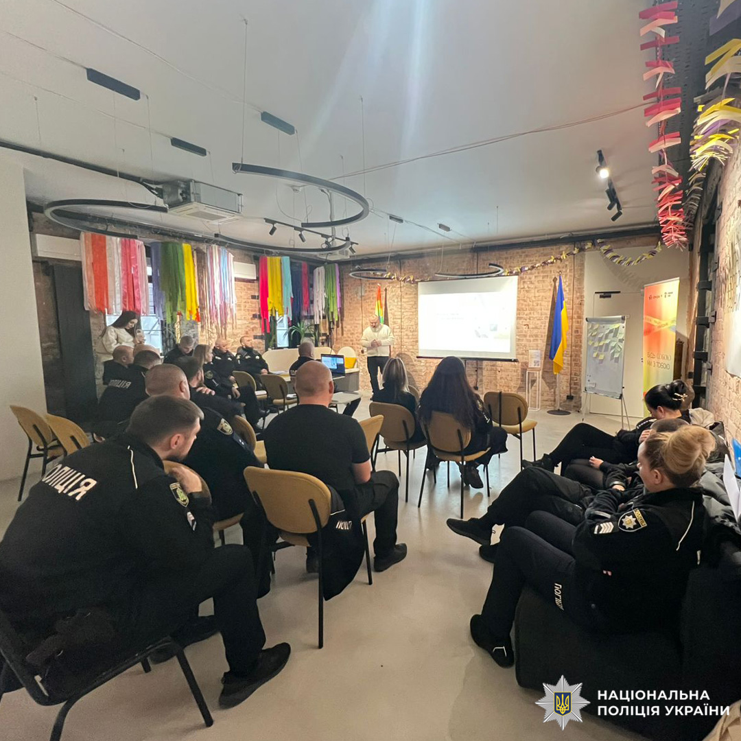 Поліцейські у формі беруть участь у тренінгу за участю представників МБФ «Альянс громадського здоров’я»; у приміщенні українські прапори та декоративні стрічки; доповідач проводить презентацію біля екрана.