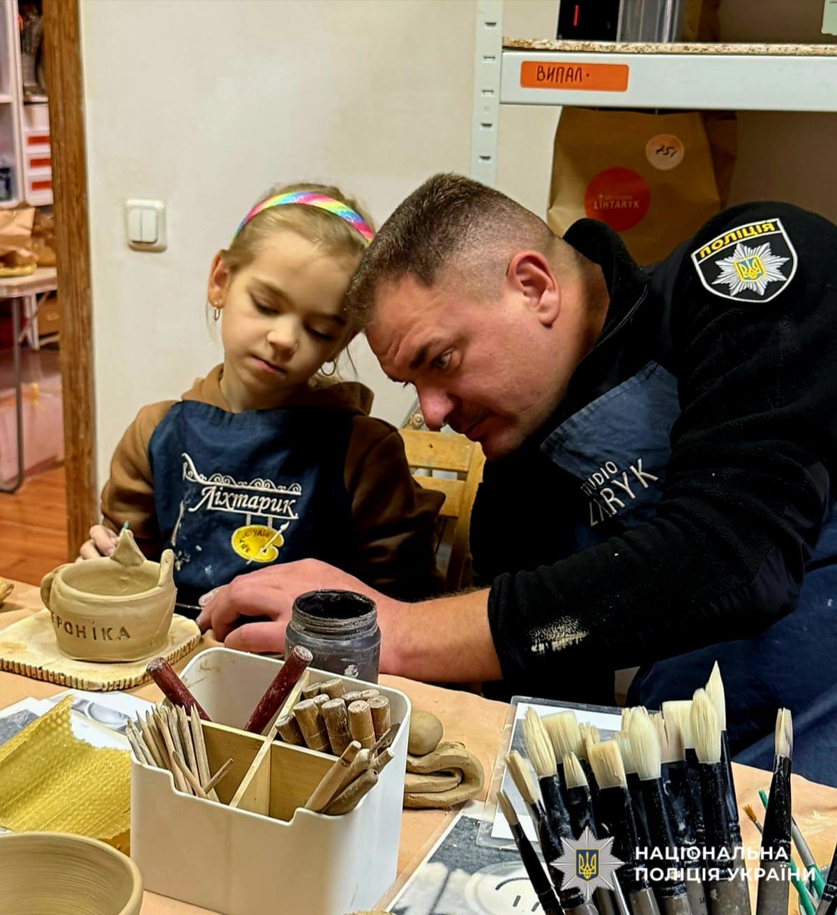 На фотографії зображено зустріч правоохоронців з ветеранами та їх родинами. Учасники зустрічі працювали з глиною, створюючи різноманітні предмети домашнього вжитку.
